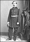 Officer with moustache in dark dress military uniform with long coat