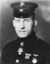 Head and shoulders of man in circa 1920 U.S. Marine dress uniform, wearing a star-shaped medal hanging from a ribbon under his collar.