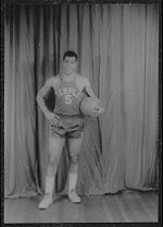 A man, wearing a jersey with a word "TEMPLE" and the number "5" written in the front, is holding a basketball while posing for a photo.