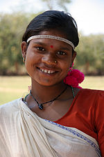 A dark-skinned woman with a bindi, tilting her head and smiling at the camera