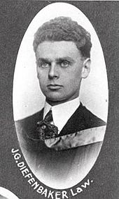Formal photo portrait of Diefenbaker at age 23. His short dark hair is very thick and curly and has been combed back smoothly, and his face is thinner than at an older age. He is formally dressed with a stiffened shirt collar and wears an academic hood. Picture is inscribed "J.G. Diefenbaker, law".