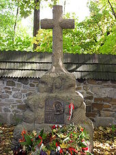 A stone cross atop a large rock. A plaque mounted on the rock reads: "Ostaszkow, Starobielsk, Kozielsk, Katyn 1940", followed by "Zwiazek Sybrakow".