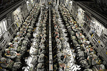 Paratroopers in four rows sit strapped in.