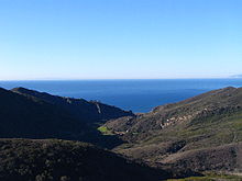 A large valley between arid chaparral-covered hills, opening towards the ocean.