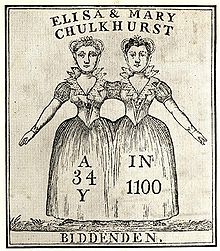 Two women, apparently joined at the shoulder. The women are wearing a single skirt between them. The women's facial features and hair colours are not identical.