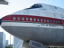  A side view of the nose of 747 prototype, which is painted white, with a red wide cheatline, and a metallic underside