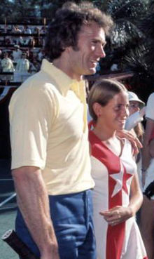 A man stands next to a girl as they both face to the left, smiling.