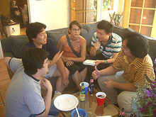 Five people sitting on a couch and a chair in a semicircle around a small table.