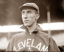 A man wearing a baseball cap and jersey with "Cleveland" written across the chest looks to the left.