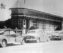 Black and white photo of a building with cars parked in front