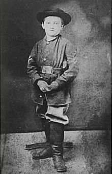 Boy wearing Union uniform, hat and boots, looks into the camera.