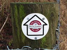 Wooden post with circular waymarker showing an arrow containing the logo of Butcombe Brewery