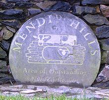 Weathered blue circular plaque bearing the logo of the Mendip Hills Area of Outstanding Natural Beauty