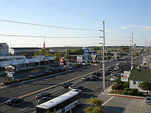 A wide, busy, divided highway is flanked by hotels, restaurants, and other businesses serving beach visitors.