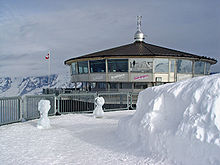 A restaurant in a snowy environment. Mountains can be seen in the background.