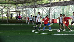 Men playing football on artificial grass pitch.