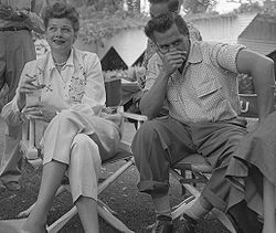 Casual shot of Ball and Arnaz outside, sitting in director chairs. Ball is smiling slightly; Arnaz is looking the other way with his hand over his mouth.