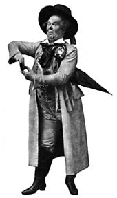 Actor in exaggerated stage pose, wearing a wide-brimmed hat and long heavy coat, carrying an umbrella