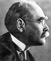Profile of the balding head of a man in a high collar, tie and coat and with a serious expression. He has bushy eyebrows and a moustache.