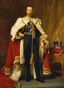 Full-length portrait in oils of a blue-eyed, brown-haired man of slim build, with a beard and moustache. He wears a British naval uniform under an ermine cape, and beside him a jewelled crown stands on a table.