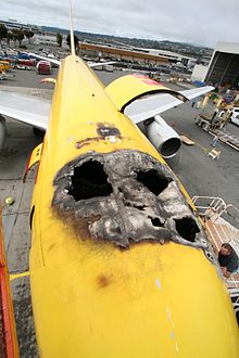 The top of a fire damaged airplane with several holes burnt through the top.
