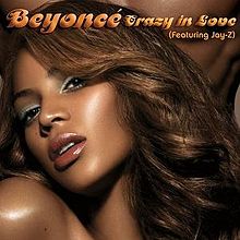 Left side of the face of a brunette woman with soft make-up. Behind her, the chest of a naked man is visible. The words "Beyoncé", "(featuring Jay-Z)" and "Crazy in Love" are written above her image.