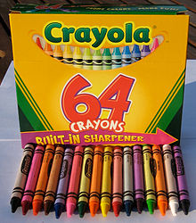 Crayola yellow and green 64-color box with 16 of the crayons from the box arrayed in front of it