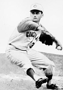 A man wearing a baseball uniform with "Cincinnati" written across the chest and a "C" on the cap caught in the midst of pitching a baseball.