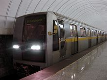 Modern, silver-colored train pulling into a station