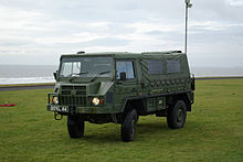 four-wheeled vehicle on green field, it has a canvas canopy over the rear and at the extreme rear a radio mast has been extended