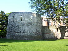 Ancient stone wall and roofless tower with narrow windows.