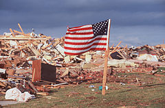 An American Flag blows in the wind next to the remains of a home destroyed by the tornado