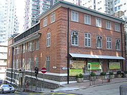 Upper elevation of three storey red brick corner-building with flat roof