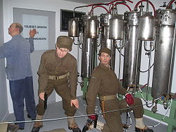 Two saboteurs and a facility employee shown adjacent to the electrolysis chambers.