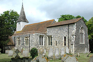 A flint church with a red tied roof and a tower at the west end, seen from the southeast