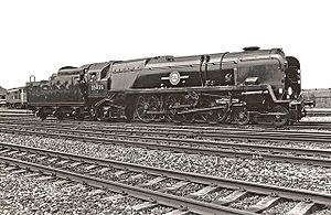 A posed side-and-front view of the rebuilt form of the locomotive, standing in the sidings of a locomotive depot. The locomotive is of conventional appearance, with a visible boiler and no flat covering plates. Smoke deflectors are fitted at the front of the locomotive.